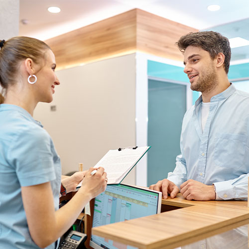 Young man chking in to day surgery clinic and chatting with nurse